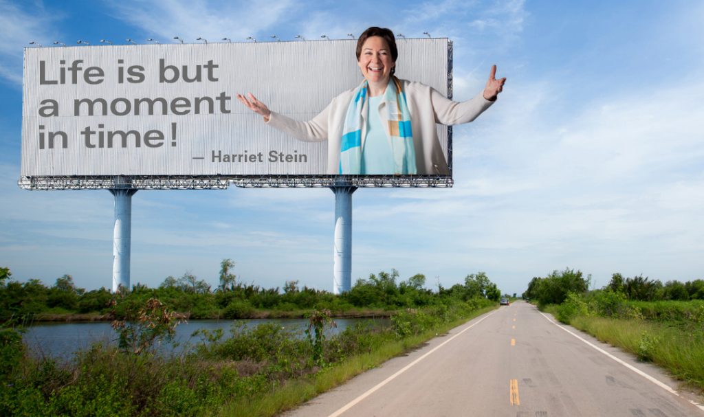 Harriet on a billboard that says "Life is but a moment in time!"